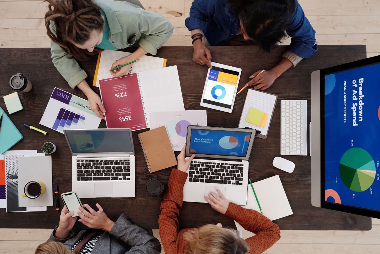 Une équipe diversifiée travaillant ensemble sur des stratégies de marketing digital autour d’une table, avec des ordinateurs portables et des tablettes.
